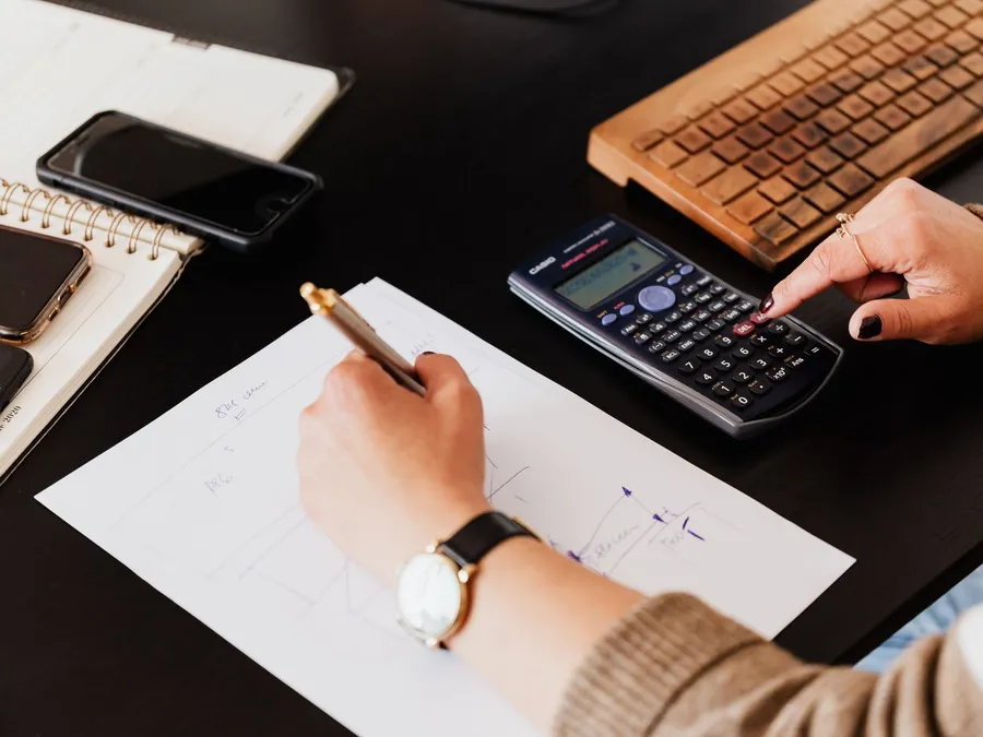 Bookkeeper Writing Down on Paper while using Calculator