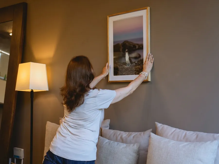 Woman in White Shirt Hanging a Frame on the Wall