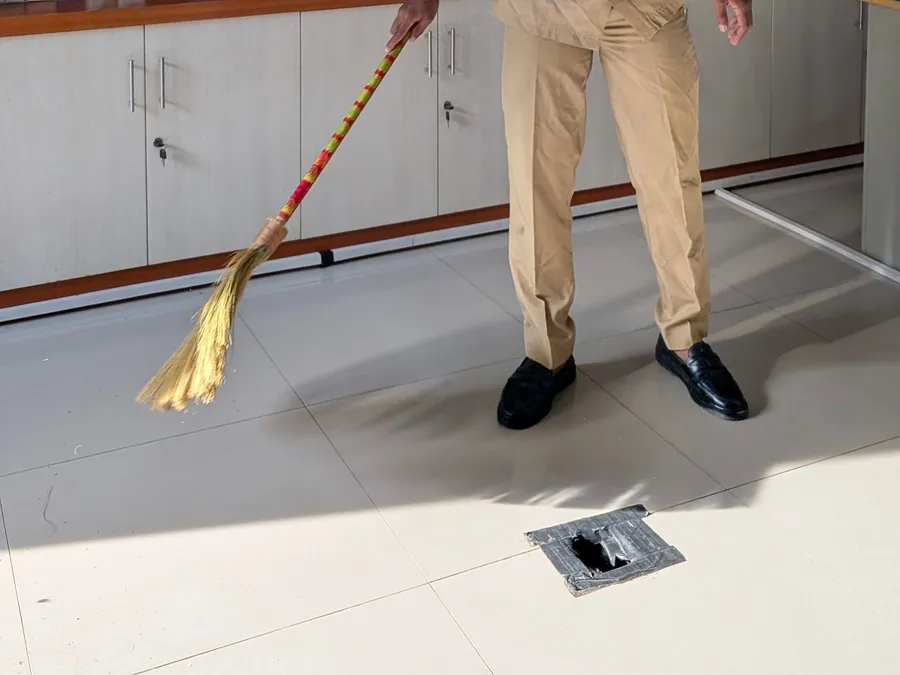 Uniformed Worker Sweeping Office Floor