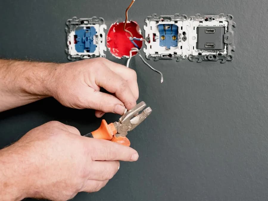 An Electrician Using Pliers to Repair the AC Power Plugs and Sockets