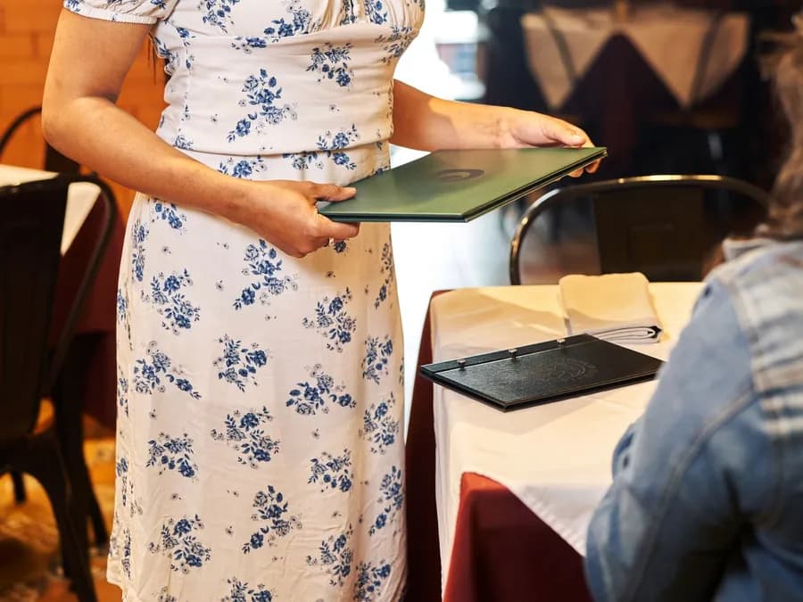 Smiling waitress serving customer in cozy restaurant