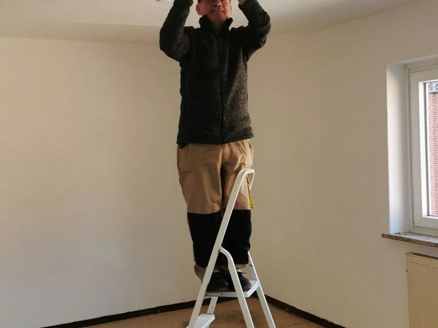 Man Fixing Ceiling Light in Empty Room