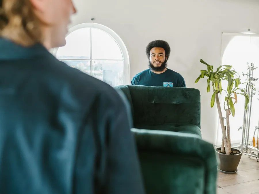 Two Men Moving a Green Couch