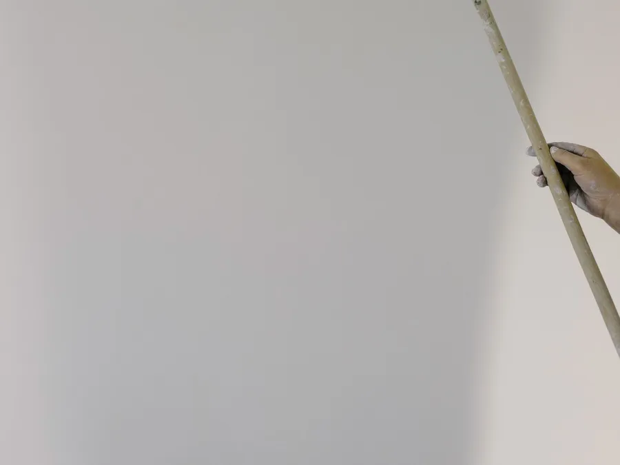 Crop faceless painter rolling walls in light apartment