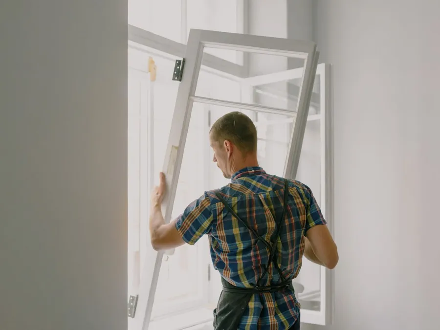 Unrecognizable workman installing window in house during renovation process