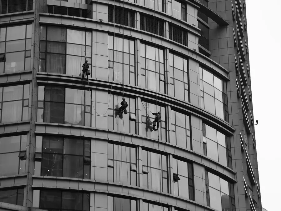 People Hanging on the Building while Cleaning the Glass Windows